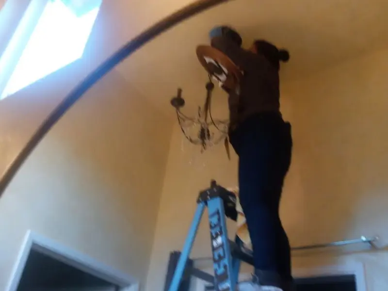 Electrician installing a chandelier in a Buhl residence